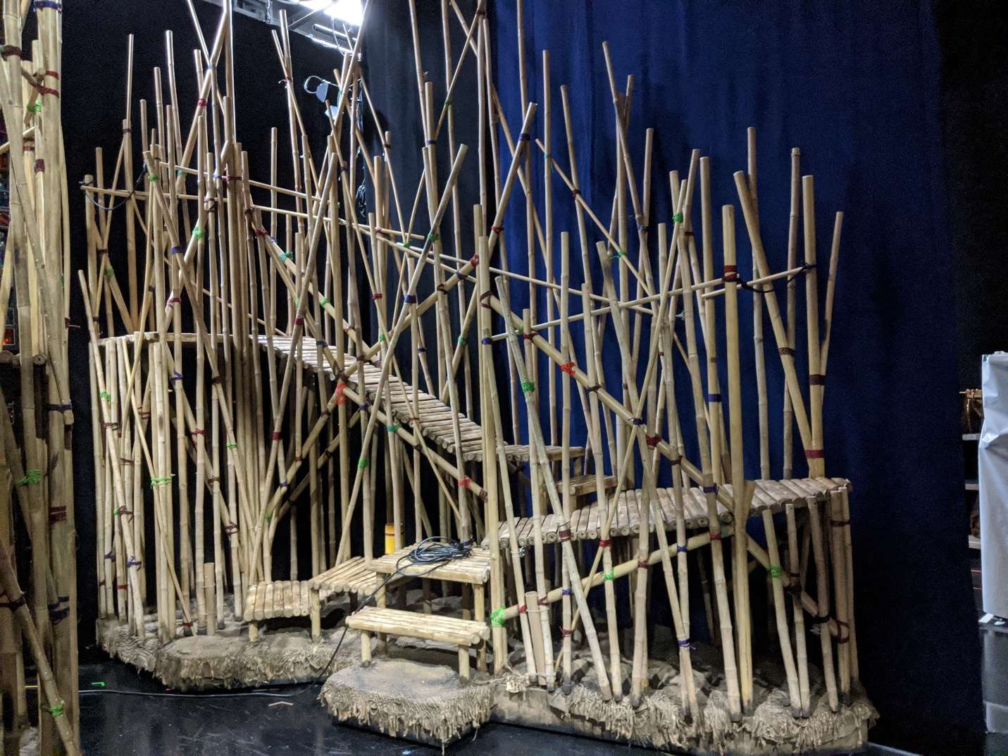 Multi-level engineered bamboo theatrical staging structure built by Matthew Clark, photographed on a darkened stage.