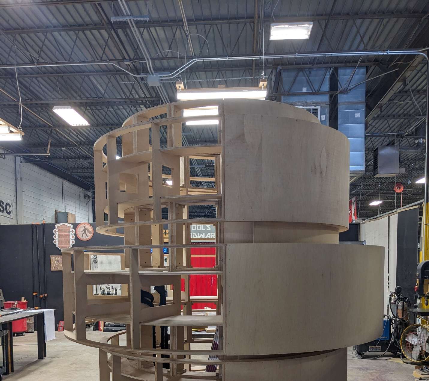 Exposed internal plywood rib framework of a curved architectural display column, showing radius-bending and structural joinery.